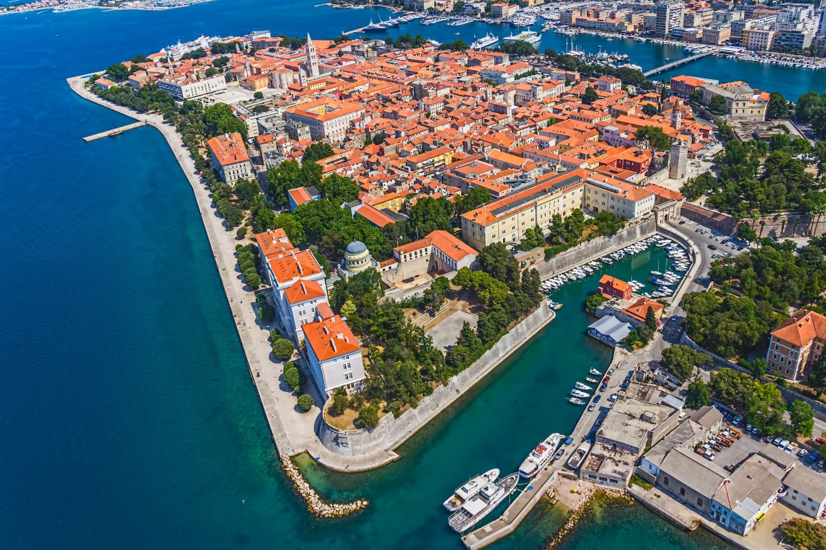 Vogelperspektive auf die Altstadthalbinsel von Zadar mit orangefarbenen Dächern, dem Stadtpark und dem Bootshafen